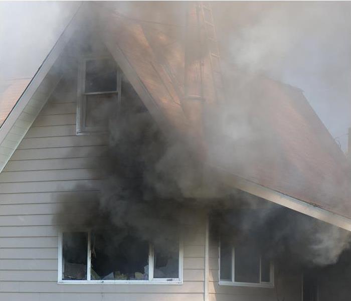 black smoke coming out of windows from a burning house