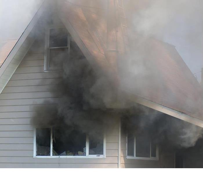 black smoke coming out of windows from a burning house