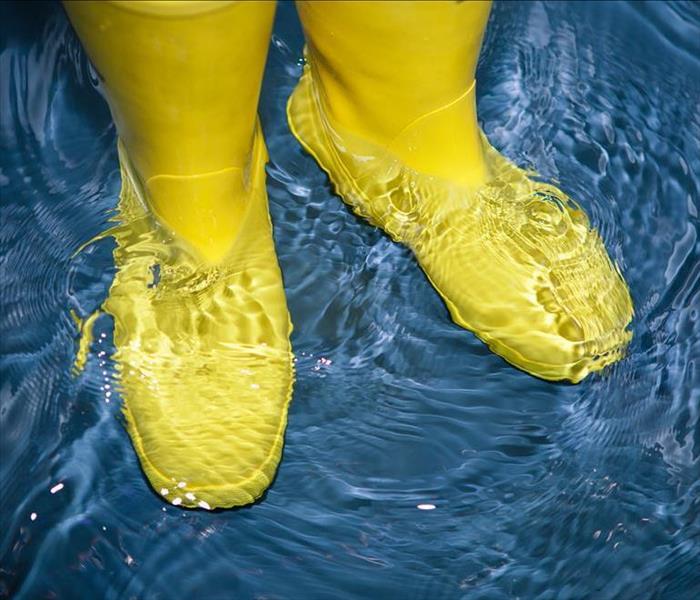 person standing in water wearing yellow rain boots